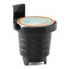 Black pod chamber of single-serve coffee maker with orange-topped coffee insert.