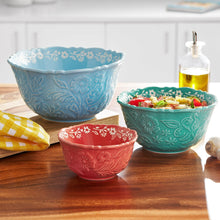 Three embossed stoneware bowls in light blue, teal, and red on tabletop.