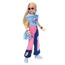 Disney Ily fashion doll wearing pink pants, blue cap-sleeve top, sunglasses, and sneakers.