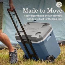 Blue hard chest wheeled cooler with extended handle outdoors.