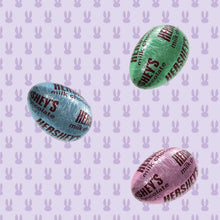Three wrapped milk chocolate Easter eggs in green, purple and blue wrappers