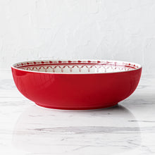 Red stoneware serving bowl with cream top rim and patterned interior border