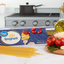 Spaghetti pasta box with uncooked spaghetti and tomatoes on countertop
