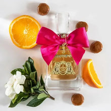 Perfume bottle with magenta bow and gold label, surrounded by orange and flower accents