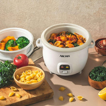 White rice cooker steamer pot with domed lid, filled with steamed food