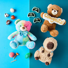Multicolor bear plush toy with bow tie on its side, among birthday party decorations.