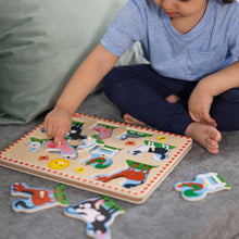 Child pressing wooden peg pieces onto a farm animal sound puzzle board