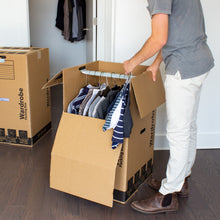 Kraft wardrobe moving box opened with folded clothes inside, side flaps folded
