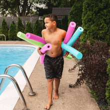 Swim pool noodles in green, pink, and teal held by a child by the pool