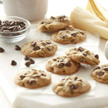 Chocolate chip cookies on dark non-stick baking tray with parchment