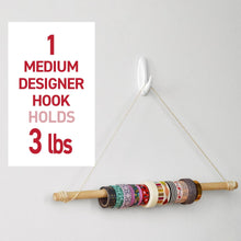 White medium designer wall hook holding twine and a small hanging rod