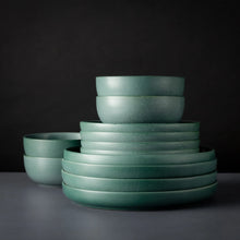 Caspian green ceramic bowls and plates, stacked in a tiered arrangement