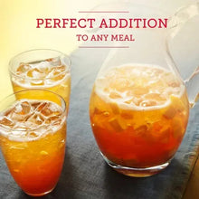 Glass of sweetened peach iced tea with ice cubes and pale foam
