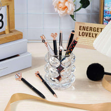 Black fancy pens with rose-gold accents on a desk with a pen holder