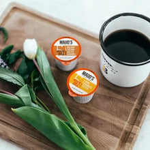 Coffee pods variety pack with pod cups and dark coffee mug on wooden board