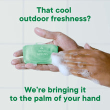 Irish Spring deodorant soap bar in hand with white lather, bright green bar.