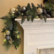 Pre-lit artificial garland with dark green needles, gold and silver ornaments, warm twinkle lights