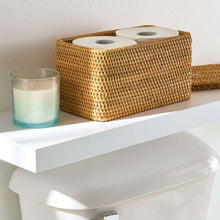 Brown rattan organizer basket with lid open, holding two roll dispensers inside.
