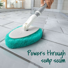 Extendable scrubber tool with green pad on tiled floor, angled for scrubbing