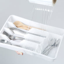 Clear stretch wrap covering a tray of cutlery and food, wrapped plastic film