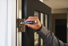 Hand applying precision pen lubricant along a door hinge using the pen’s white nozzle tip