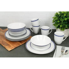 Ceramic dinnerware set with stacked plates, bowls, and mugs in blue stripe trim