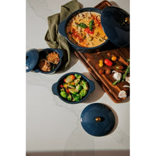 Blue ceramic casserole set with three pots and lids; one uncovered with prepared food