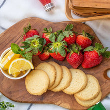 Gluten-free cookie slices on a wooden board with strawberries and lemon