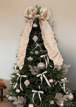 Decorated Christmas tree with champagne baubles, bow garlands, heart ornaments, and glitter picks.