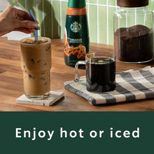 Iced coffee drinks with creamer bottle and coffee mugs on a wooden table