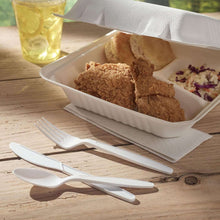 White disposable plastic utensils on wooden table with takeout food containers