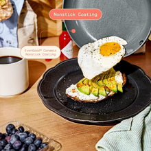 Dark ceramic nonstick skillet with lid, showing fried eggs