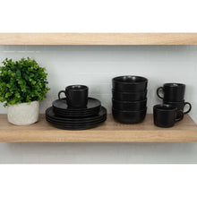 Matte black dinnerware set arranged on a shelf: plates, bowls, and handled mugs