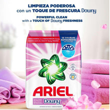 Laundry detergent powder bag with ARIEL and Downy, pink ribbon design, beside towels