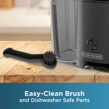 Cleaning brush tool for fruit and vegetable juicer next to clear pulp container