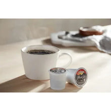 White ceramic mug with dark coffee and Keurig pod on counter