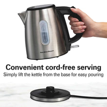 Stainless steel electric kettle with black handle lifted from base for pouring