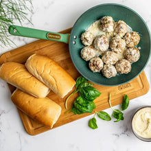 Green nonstick fry pan on a wooden board during cooking