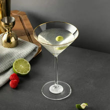 Gold-rim martini glass with clear bowl, filled drink and lime slice