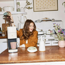 White single-serve coffee maker on kitchen counter with cups beside it