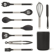 Assorted black silicone cooking utensils with metal handles and ribbed holder
