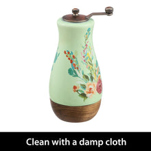 Ceramic pepper mill with floral design, arched metal grinder handle and knobs, wood base