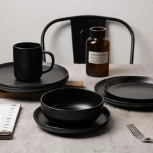 Black stoneware dinnerware set with stackable plates, bowls, and mugs