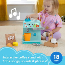 Teal coffee café learning toy stand with cups and accessories beside a toddler