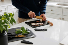 Black knife set with cutting boards and sheathed blades on kitchen counter