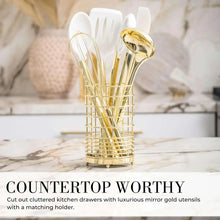 Countertop utensil holder filled with white silicone cooking tools and gold handles