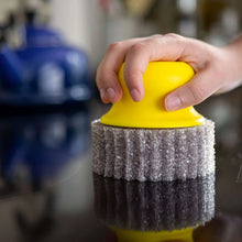 Hand holding yellow scrubber face on gray scouring sponge pad