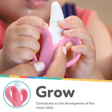 Pink infant toothbrush held by hands with white bristle end