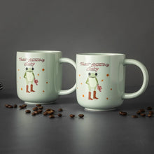 Two light green ceramic mugs with baby frog in boots, “That’s Showbiz Baby” lettering