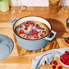 Cornflower blue enameled Dutch oven with side handles, round pot filled with fruit dessert